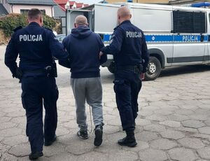 policjanci prowadzą zatrzymanego.