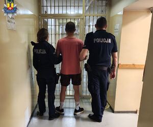policjanci prowadzą zatrzymanego.