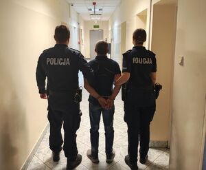 policjanci prowadzą zatrzymanego.