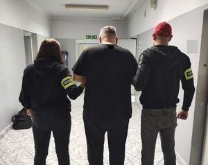 policjanci prowadzą zatrzymanego.
