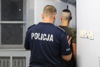 policjant prowadzi do celi zatrzymanego