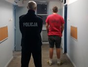 umundurowany policjant prowadzi zatrzymanego do celi w PDOZ