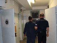 policjant prowadzi zatrzymanego w policyjnym areszcie do celi