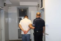 policjant prowadzi zatrzymanego w policyjnym areszcie do celi