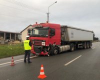 policjant pracujący na miejscu wypadku drogowego, w tle samochód ciężarowy z naczepą