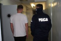 umundurowany policjant prowadzi zatrzymanego do celi w pomieszczeniu dla osób zatrzymanych w wieluńskiej komendzie