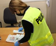 policjantka w kamizelce z napisem POLICJA zabezpiecza znalezione w trakcie przeszukania substancje