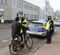 umundurowani policjanci wręczają rowerzyście kamizelkę odblaskową