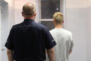 umundurowany policjant prowadzi zatrzymanego do celi