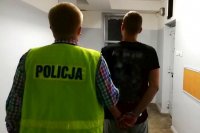 nieumundurowany policjant w kamizelce z napisem policja prowadzi zatrzymanego na przesłuchanie