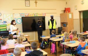 umundurowani policjanci stoją w klasie i prowadzą pogadankę z dziećmi