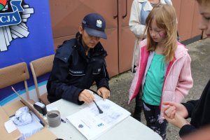 policjantka na stoisku profilaktycznym robi odbitki linii papilarnych