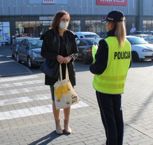 policjantka wręcza przechodniom kamizelki odblaskowe