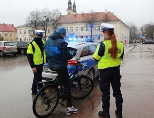 policjant i policjantka ruchu drogowego wręczają element odblaskowy rowerzyście