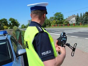 policjant trzyma w ręku  urządzenie do mierzenia prędkości pojazdów