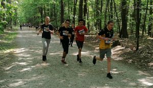 uczestnicy biegną alejkami lasu miejskiego