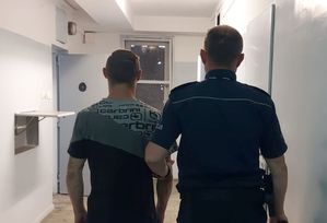 policjant prowadzi zatrzymanego do celi