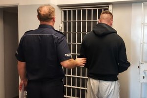 policjant prowadzi zatrzymanego do celi