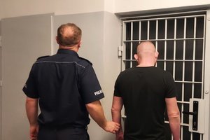 policjant prowadzi zatrzymanego do celi
