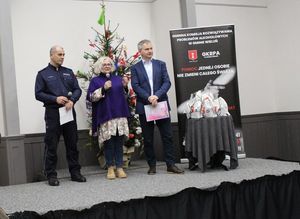 W sali Dworca Kulturalnego Wieluń Dąbrowa na scenie dyrektor Wieluńskiego Domu Kultury mówi przez mikrofon, stoi wspólnie na scenie z naczelnikiem Wydziału Prewencji wieluńskiej komendy oraz przewodniczącym Gminnej Komisji Rozwiązywania Problemów Alkoholowych w Gminie Wieluń.