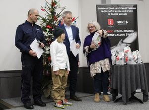 W sali Dworca Kulturalnego Wieluń Dąbrowa na scenie dyrektor Wieluńskiego Domu Kultury wręcza nagrodę laureatowi konkursu, stoi wspólnie na scenie z naczelnikiem Wydziału Prewencji wieluńskiej komendy oraz przewodniczącym Gminnej Komisji Rozwiązywania Problemów Alkoholowych w Gminie Wieluń.