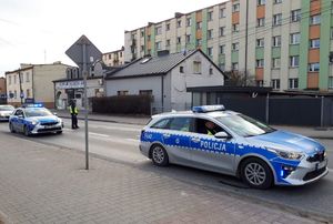 W miejscu wypadku do którego doszło na terenie miasta Wieluń stoją radiowozy policyjne. policjant kieruje ruchem.