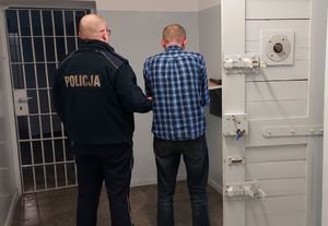 Policjant prowadzi zatrzymanego do celi.