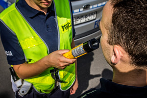 Policjant badający stan trzeźwości urządzeniem alkoblow.