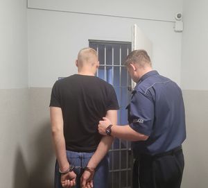 Policjant prowadzi zatrzymanego do celi.