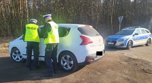 Policjanci stoją przy kontrolowanym aucie.