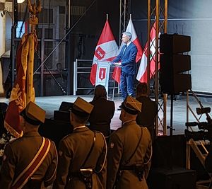 Scena, na której przemawia Wicepremier Rady Ministrów , wokół zgromadzeni goście uroczystości.