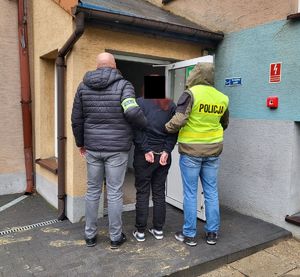 Policjanci prowadzą zatrzymaną do budynku komendy policji.