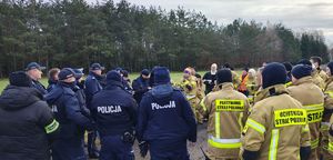 Policjanci i strażacy w miejscu koncentracji sił w miejscu gdzie będą prowadzone poszukiwania zaginionego.
