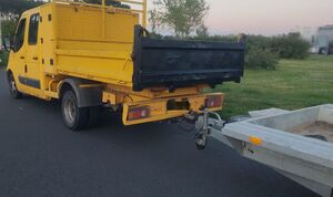 Skradziony samochód oraz częściowo widoczna lawet stoją na drodze.