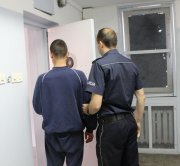 kolorowe zdjęcie przedstawiające umundurowanego policjanta prowadzącego zatrzymanego za pobicie.