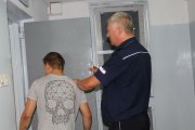 kolorowe zdjęcie przedstawiające policjanta osadzającego zatrzymanego w policyjnej celi