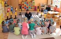 policjantka z przedszkolakami w trakcie pogadanki edukacyjno- profilaktycznej na temat bezpieczeństwa
