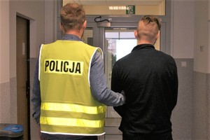 korytarz komendy, policjant prowadzi zatrzymanego mężczyznę.