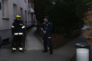 policjant wspólnie ze Strażakiem zabezpiecza tylne wejście do budynku starostwa