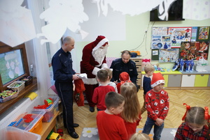 Mikołaj rozdaje prezenty wspólnie z policjantami.