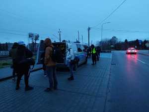 pasażerowie autobusu w tle radiowóz.