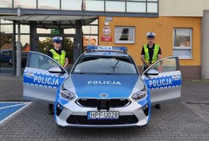 policjanci ruchu drogowego przy radiowozie i przed Komendą Powiatowa Policji w Wieruszowie.