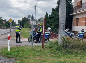 policjant mierzy prędkość, obok zaparkowane policyjne motocykle.