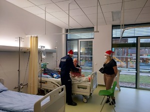 policjant z pracownikiem cywilnym wieruszowskiej komendy wręczają prezent chłopakowi  w sali szpitala.