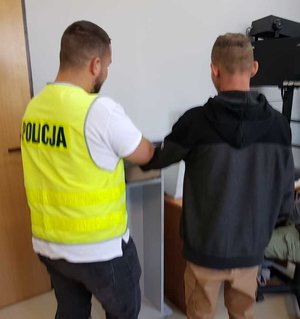 policjant z zatrzymanym pobiera odciski palców.