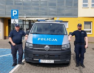 widzimy dzielnicowych na tle policyjnego radiowozu.