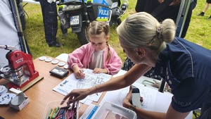 widzimy policjantkę odbijająca linie papilarne dziewczynce.