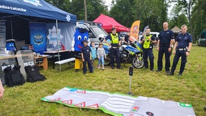 widzimy policjantów z uczestnikami imprezy na tle policyjnego motocykla i namiotu.