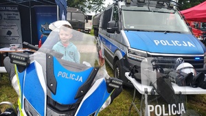 widzimy chłopca siedzącego na motocyklu na tle policyjnego namiotu.