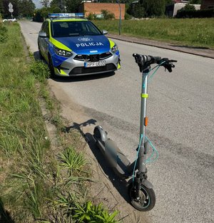 widzimy hulajnogę elektryczną na tle radiowozu.